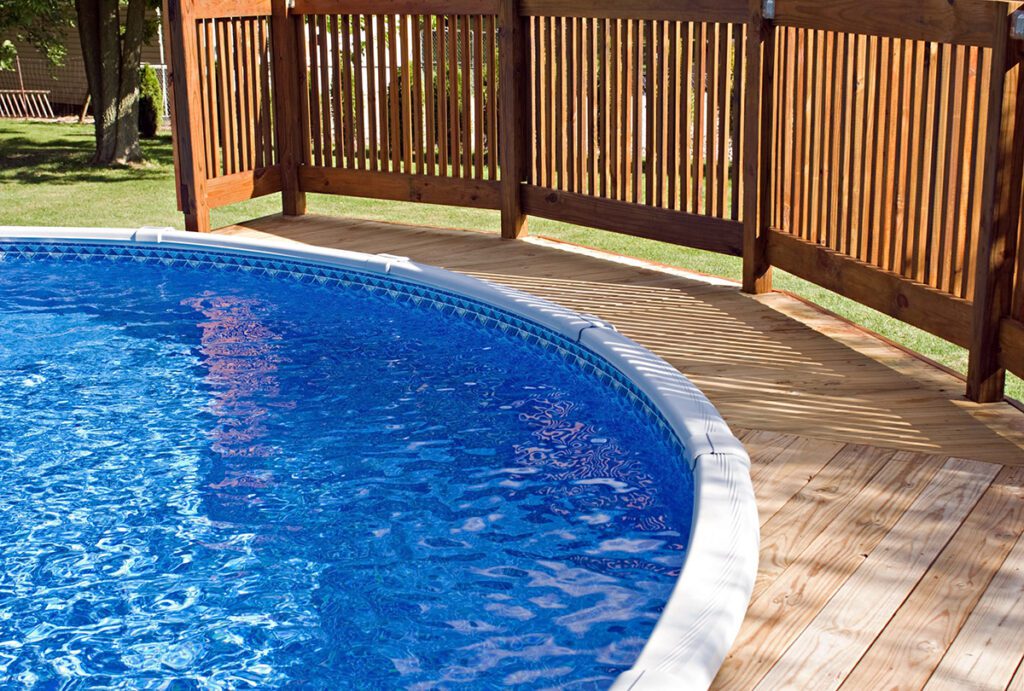 A round inset pool with a wooden deck and railing.